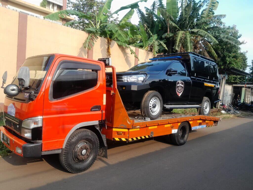 Proses menaikkan mobil ke truk derek gendong Mikano